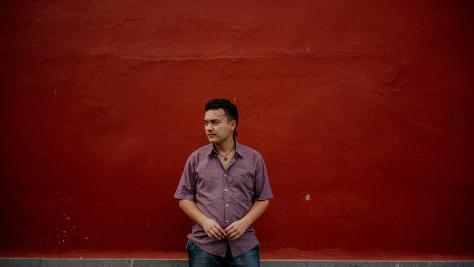 David de pie ante un muro rojo, mirando a un lado
