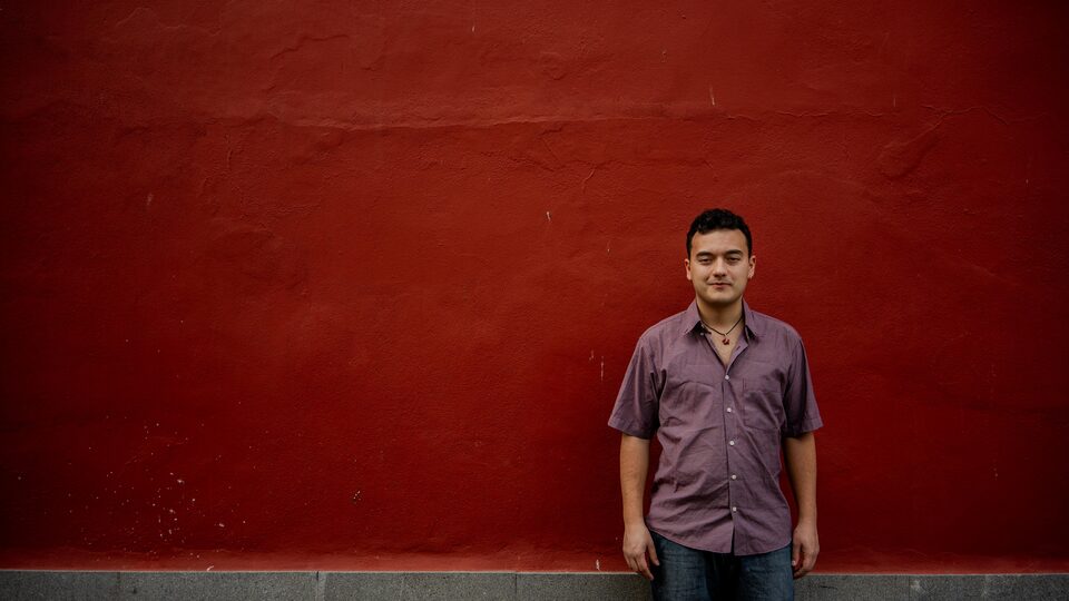 David de pie ante un muro rojo, con la mirada al frente